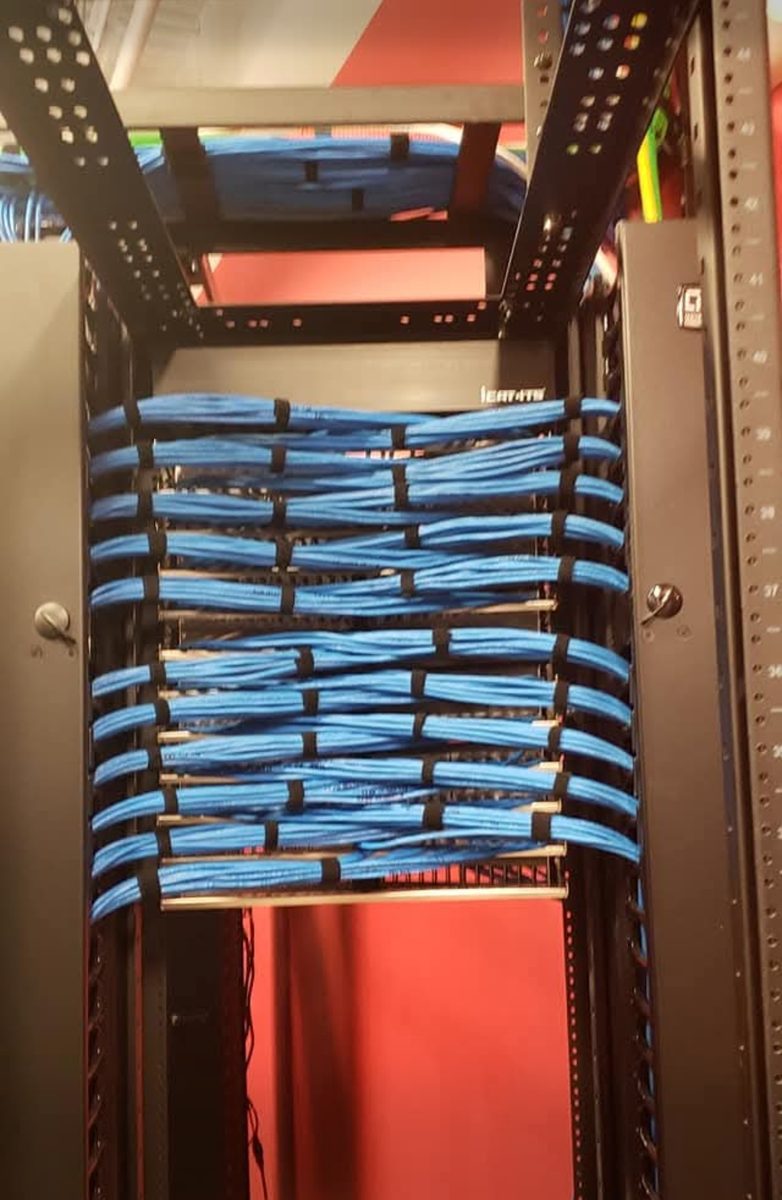 Close view of Cat6 cable bundles combed and strapped across horizontal cable managers into patch panels in a network rack, installed by DataTel 360