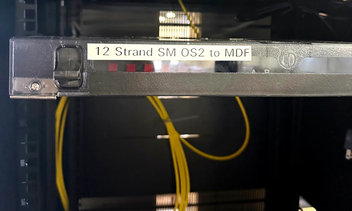 Rack-mount fiber enclosure labeled 12 Strand SM OS2 to MDF, with yellow single-mode patch cords