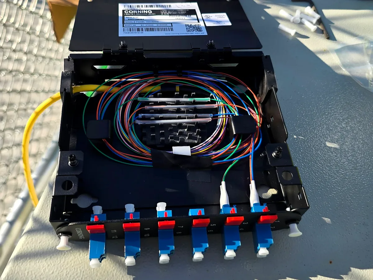 Fiber splice housing during fusion splicing, with color-coded fibers routed to LC adapters